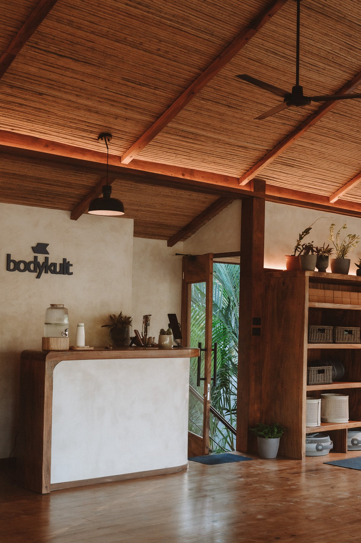 Wide view of the BodyKult reception desk and shelving with the door open to the jungle