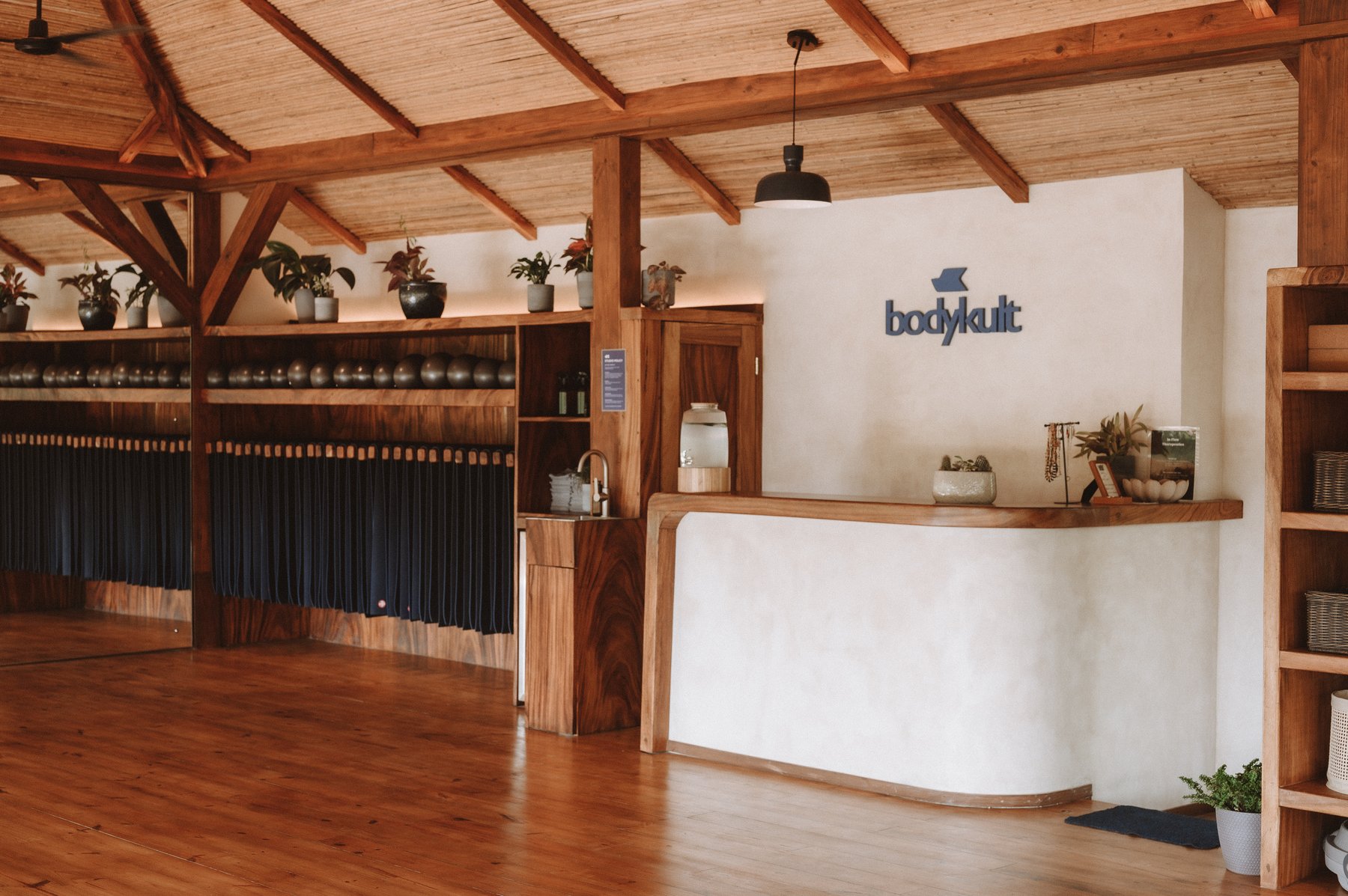 BodyKult reception desk with signature wall logo, kettlebells and plants